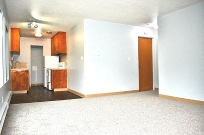 an empty living room and kitchen with a white carpet